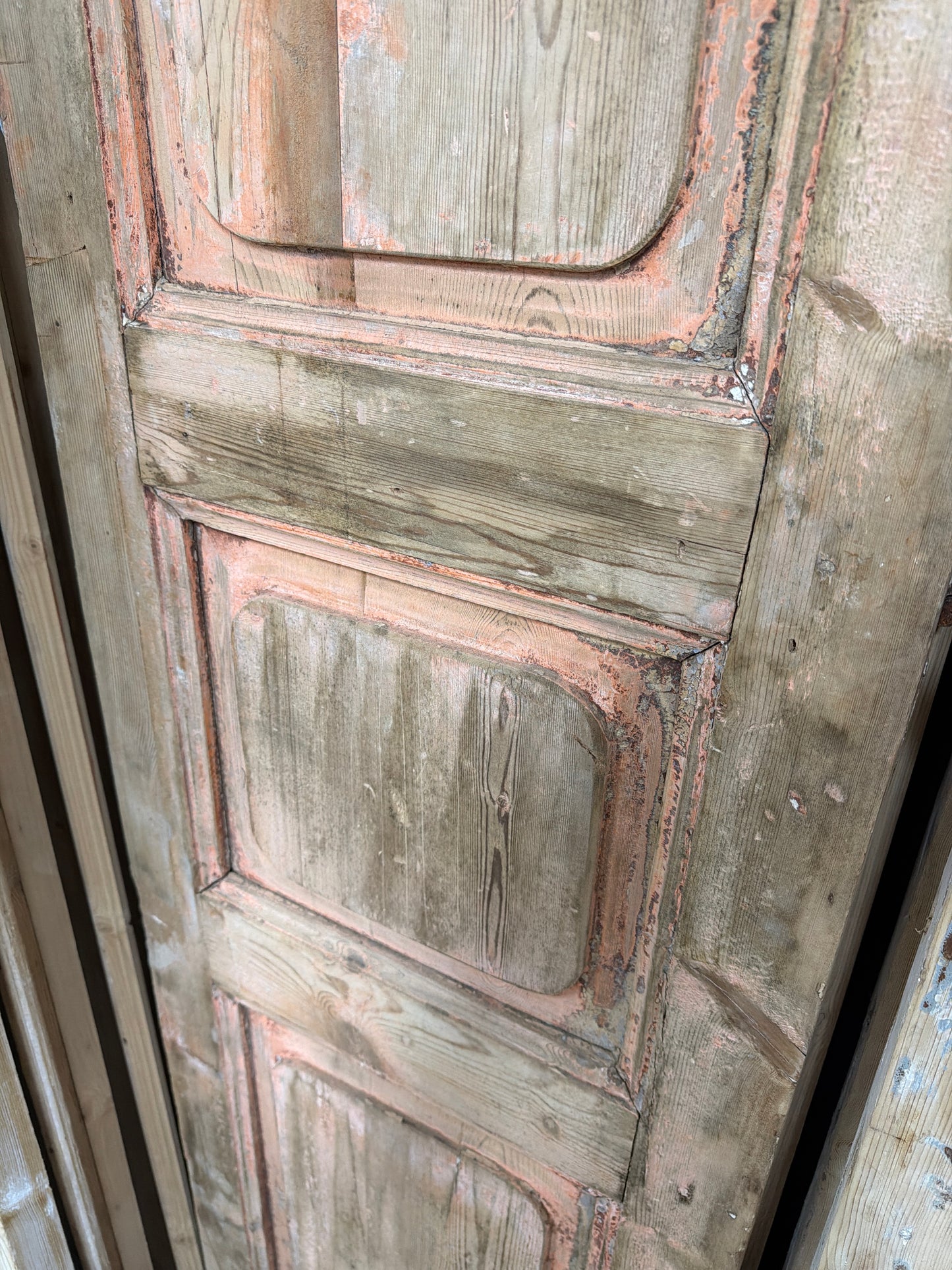 Close-up of a wooden panel with intricate carvings and peeling paint.