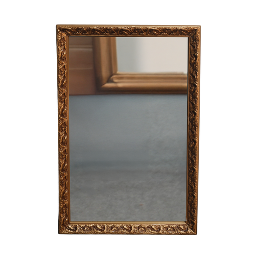 Decorative gold-framed mirror on a white background
